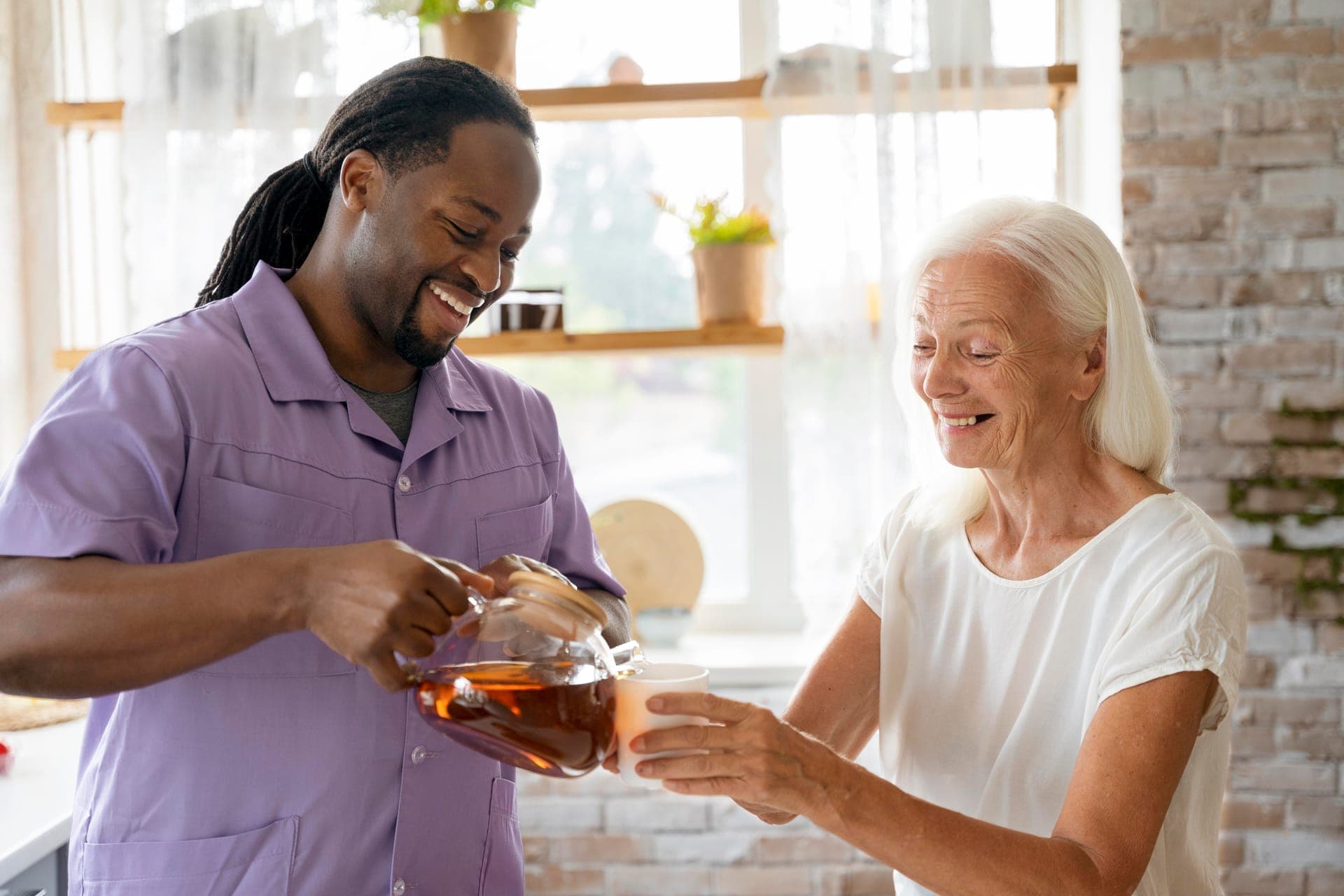 Support worker pouring tea for an older woman at home